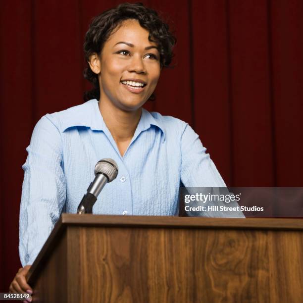 mixed race businesswoman speaking at podium - microphone debate stock pictures, royalty-free photos & images