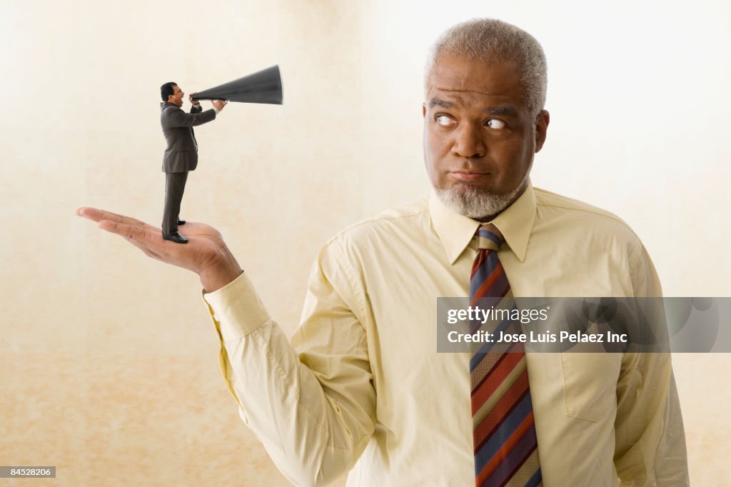 Miniature businessman speaking with bull horn to giant businessman