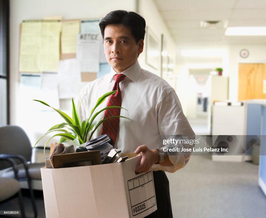 Fired Chinese businessman carrying box of personal items