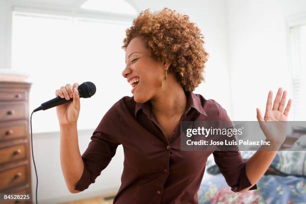 hispanic woman singing on microphone in bedroom - singing stock pictures, royalty-free photos & images