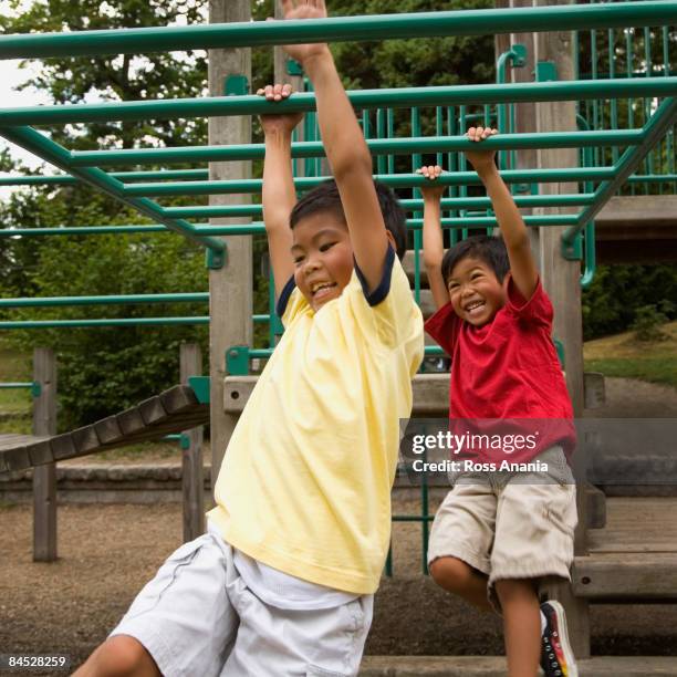 asian boys crossing monkey bars on playground - boy on monkey bars stock pictures, royalty-free photos & images