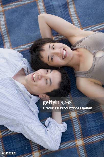 asian couple laying on blanket - saia midi stock-fotos und bilder