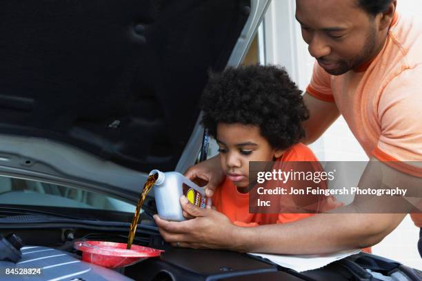 african father helping son pour oil into car engine - garage home car repair stock pictures, royalty-free photos & images