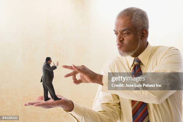 giant businessman flicking miniature businessman - dare un colpetto foto e immagini stock