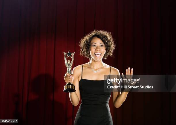mixed race woman standing on stage with trophy - champions awards ceremony stockfoto's en -beelden