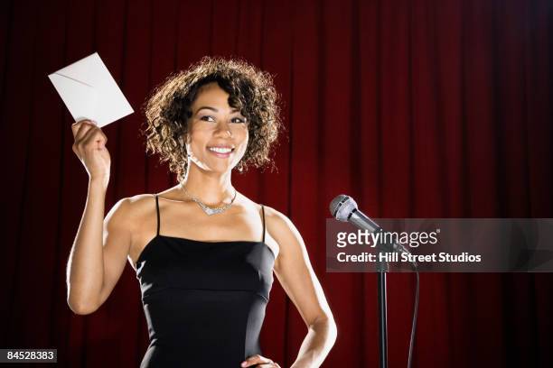 mixed race woman announcing winner on stage - presentator amusement stockfoto's en -beelden