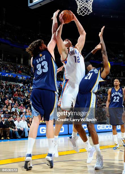 Nenad Krstic of the Oklahoma City Thunder goes to the basket against Marc Gasol and Hakim Warrick of the Memphis Grizzlies at the Ford Center on...