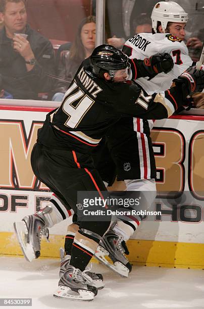 Brent Seabrook of the Chicago Blackhawks is checked into boards by Chris Kunitz of the Anaheim Ducks during the game on January 28, 2009 at Honda...