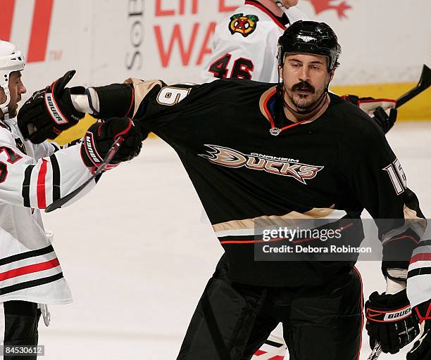 Adam Burish of the Chicago Blackhawks takes a hit from against George Parros of the Anaheim Ducks during the game on January 28, 2009 at Honda Center...