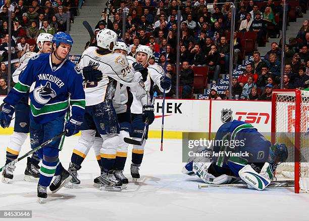 Roberto Luongo of the Vancouver Canucks lies in his net and teammate Kevin Bieksa skates away dejected while Joel Ward of the Nashville Predators is...