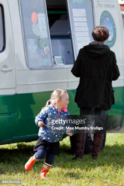 Mia Tindall runs around whilst her grandmother Princess Anne, Princess Royal talks with an ice cream vendor as they attend the Whatley Manor Horse...