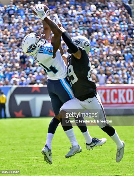 Wide receiver Corey Davis of the Tennessee Titans jumps and makes a catch against David Amerson of the Oakland Raiders during the first half at...