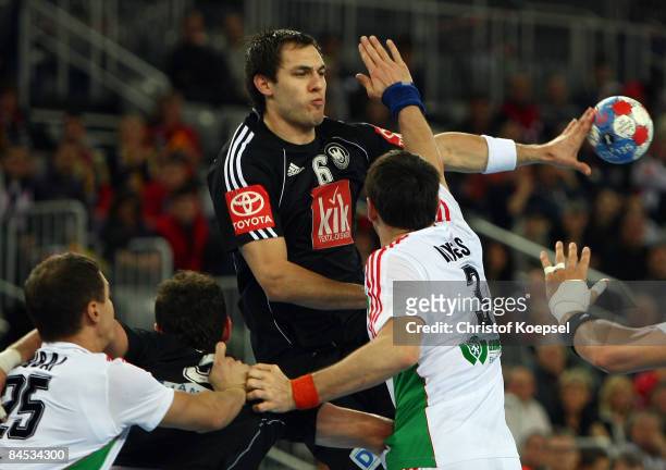 Szabolcs Zubai of Hungary and Ferenc Ilyés of Hungary tackle Michael Mueller of Germany during the Men's World Handball Championships placement match...