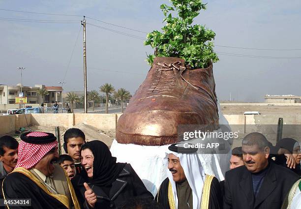 Iraqi officials share a laugh as they unveil a bronze shoe monument representing the one thrown by Iraqi journalist Muntazer al-Zaidi at former US...