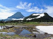 Going to the Sun Road, View of Landscape, snow fields In Glacier National Park around Logan Pass, Hidden Lake, Highline Trail, which features waterfalls, wildlife, and is surrounded by mountains including: Piegan, Pollock, Oberlin, Clements, Reynolds