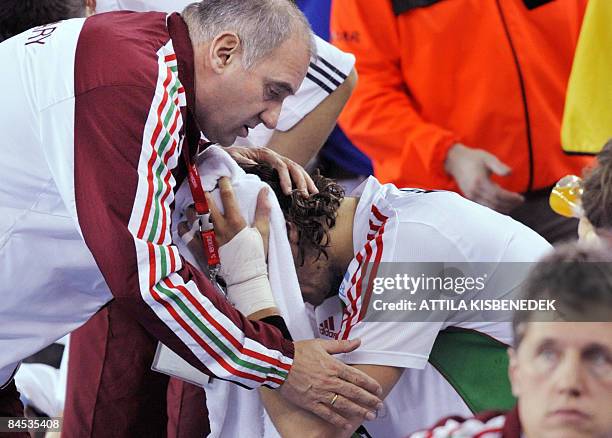 Hungarian coach Janos Hajdu comforts his best player Laszlo Nagy , covering his face with a towel as their team lost a game against Germany after...