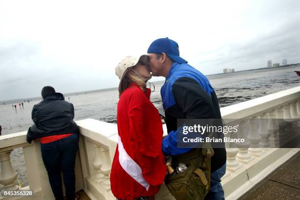 Tampa residents John and Daniel Redd share a kiss and some champagne as they join others in inspecting the extreme receding water in Tampa Bay ahead...