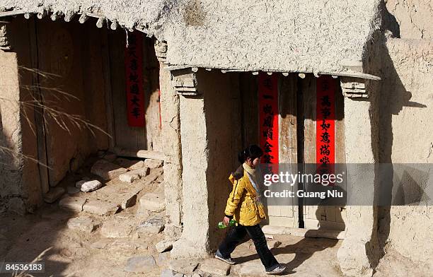 Woman walks past an inhabited Tang Dynasty building, which stands in the ancient 'Kaiyang Fort' on January 29, 2009 in Yangyuan, China. People still...