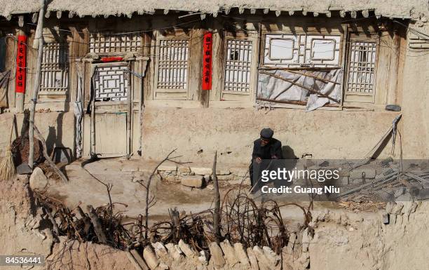 Resident sits next to an inhabited Tang Dynasty building standing in the ancient 'Kaiyang Fort' on January 29, 2009 in Yangyuan, China. People still...