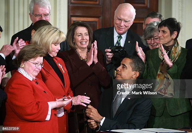 President Barack Obama hands Lilly Ledbetter a pen after signing the "Lilly Ledbetter Fair Pay Act during an event in the East Room of the White...