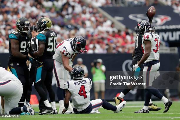 Kendall Lamm helps Deshaun Watson of the Houston Texans to his feet as Yannick Ngakoue of the Jacksonville Jaguars celebrates a fumble recovery in...