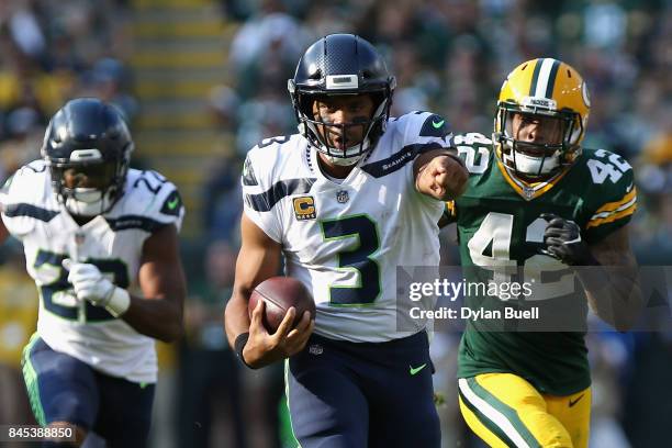 Russell Wilson of the Seattle Seahawks gestures as he runs with the ball during the second quarter against the Green Bay Packers at Lambeau Field on...