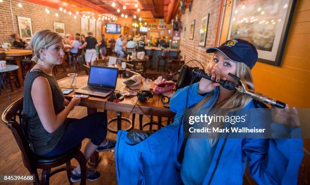 Megan Bell, right, curls her hair during a hurricane party inside Tamara's Tapas Bar prior to the arrival of Hurricane Irma September 10, 2017 in the...