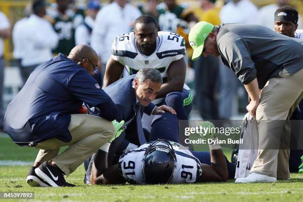 Sheldon Richardson of the Seattle Seahawks is helped by training staff during the first half against the Green Bay Packers at Lambeau Field on...