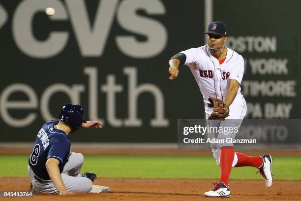 Xander Bogaerts of the Boston Red Sox turns a double play over the slide of Danny Espinosa of the Tampa Bay Rays in the seventh inning at Fenway Park...