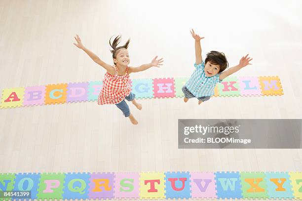 boy and girl jumping, raising hands, view from above - 日本人　英語 ストックフォトと画像