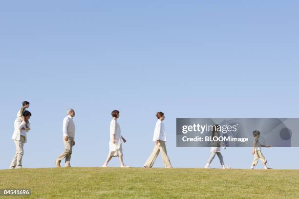 multi-generation family walking in line, side view - famiglia multigenerazionale foto e immagini stock