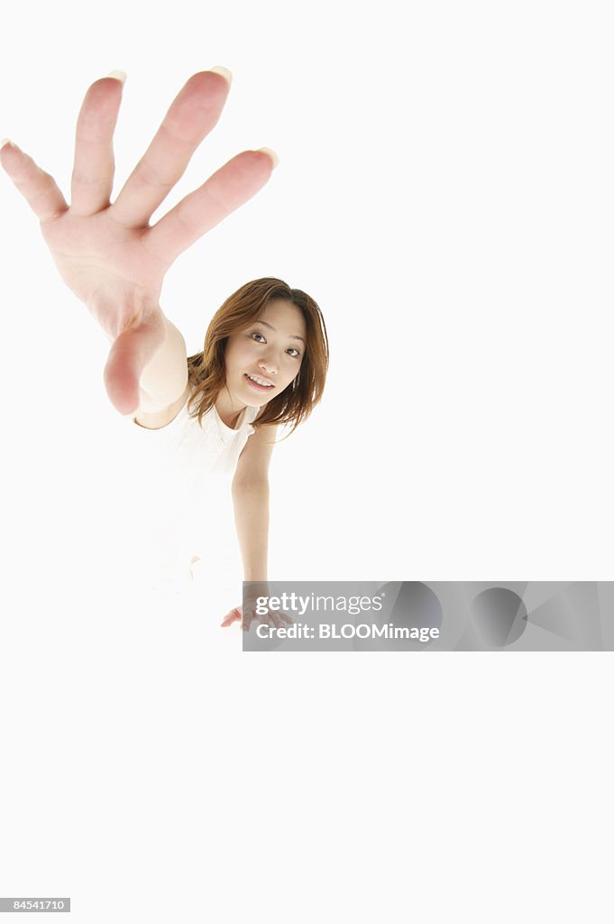 Young woman holding out hand, studio shot