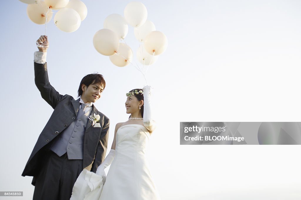 Groom and bride holding balloons