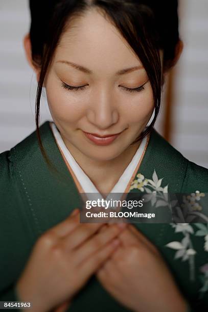 woman in kimono with hands on chest, eyes closed - woman smiling facing down stock pictures, royalty-free photos & images
