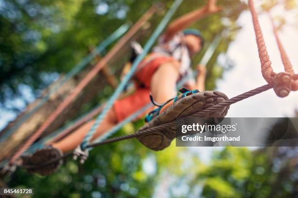 kleiner junge gehen auf linie im hochseilgarten - zip line stock-fotos und bilder