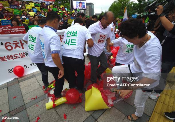 South Korean conservative activists burst balloons with yellow banners reading "ICBM" and "SLBM" - the respective acronyms for intercontinental...