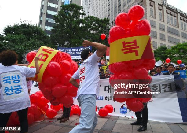 South Korean conservative activists burst balloons with yellow banners reading "ICBM" and "SLBM" - the respective acronyms for intercontinental...