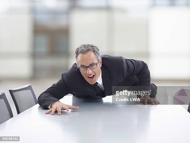 businessman climbing across conference table - china foto e immagini stock