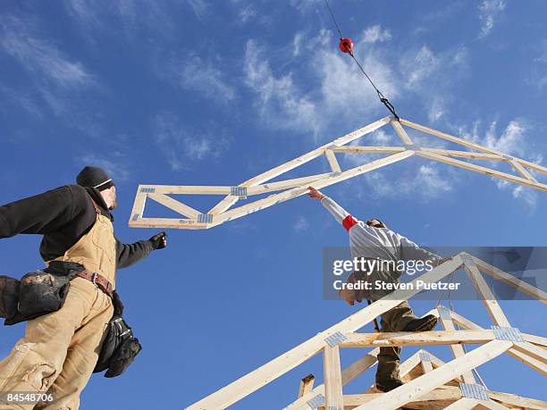 construction workers guiding roof truss into place - roof truss stock pictures, royalty-free photos & images