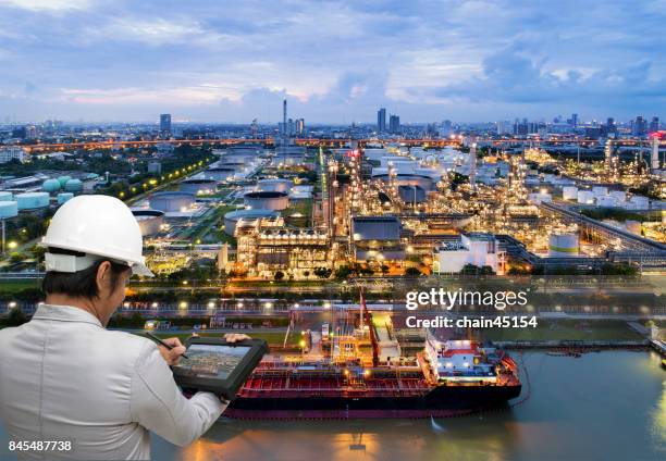 ngineer hold tablet to mangae business of oil refinery industry plant from aerial view in oil refinery industry or oil industrial. this oil refinery is in the city for refinery producing of oil and gasoline. industrial concept. - oil and gas workers imagens e fotografias de stock