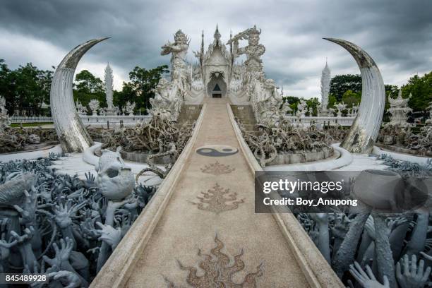 wat rong khun (white temple) in chiang rai province of thailand in the cloudy day. - hell stock pictures, royalty-free photos & images