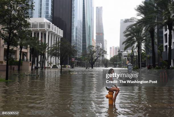 Mia Herman has an acquitance take a photo of her sitting on a fire hydrant on a flooded street as Hurricane Irma hits the area on Sunday September...