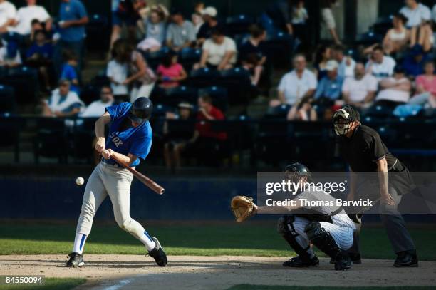batter swinging at pitch, crowd in background - battere la palla foto e immagini stock