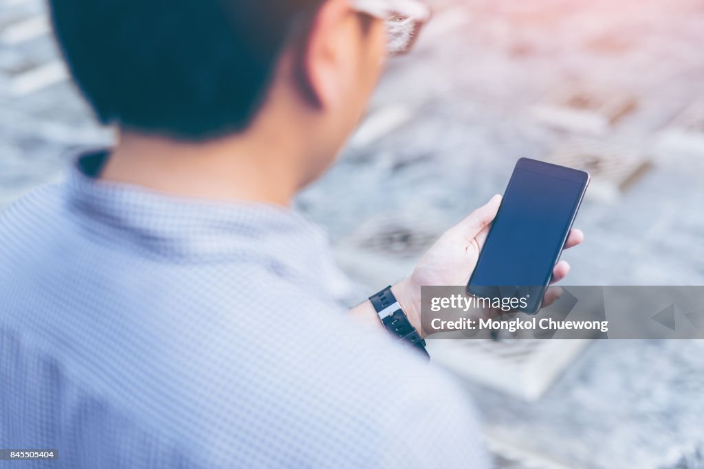 Young asian handsome businessman concentrated while reading his smartphone.