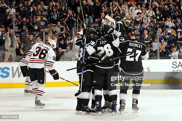 Dustin Brown, Jarret Stoll and Kyle Quincy of the Los Angeles Kings celebrate a first period goal as Dave Bolland of the Chicago Blackhawks skates by...