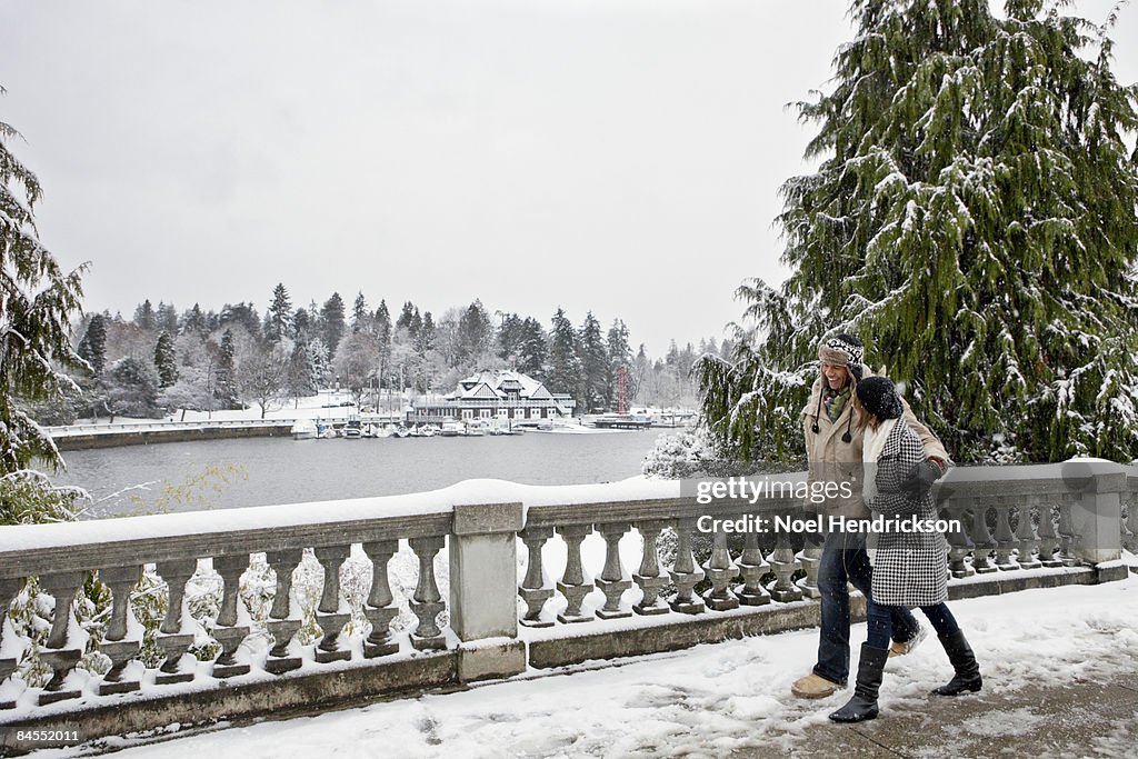 Couple walking in snow covered urban park