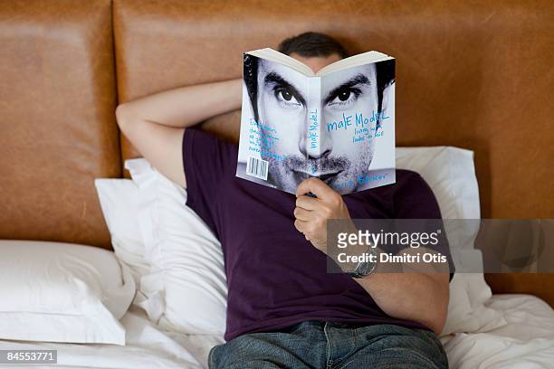 man reading with book obscuring face - holding magazine stock-fotos und bilder