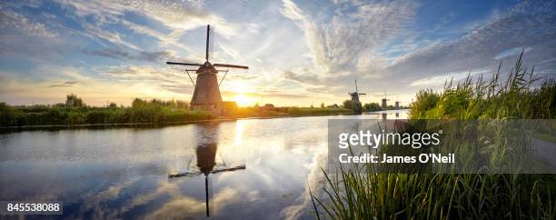 windmills and river at sunrise panoramic, kinderdijk, netherlands - netherlands stock-fotos und bilder