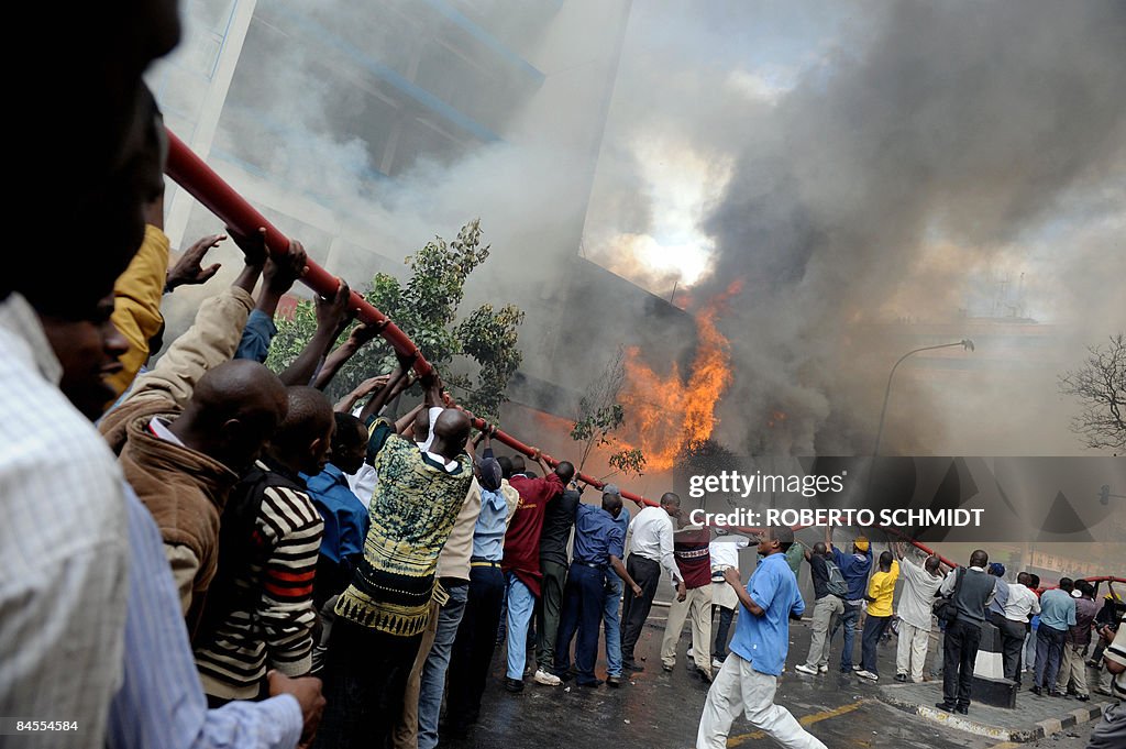 Civilians help to hold a water hose as f