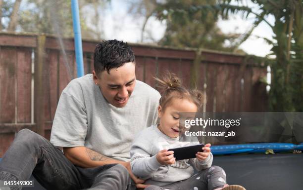 families from new zealand. - father and daughter looking at smartphone together stock pictures, royalty-free photos & images